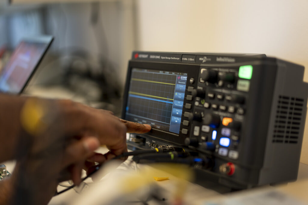 Close up of an engineer's hands using a machine to gather electric waves from the arculee's control unit.