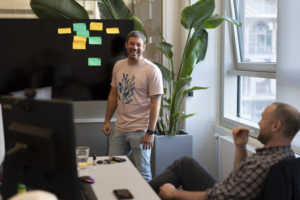 A Scrum master stands in front of a board with a few colorful post its. Scrum is a crucial part of fast development.